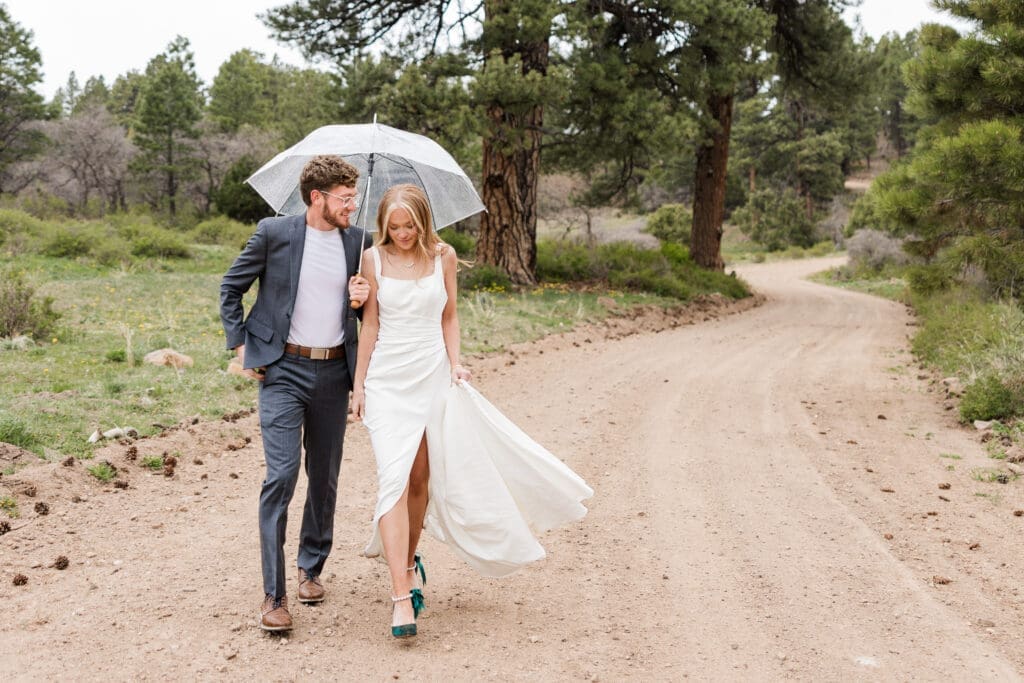 Couple walks on along a dirt road in the mountains outside of moab on their wedding day.